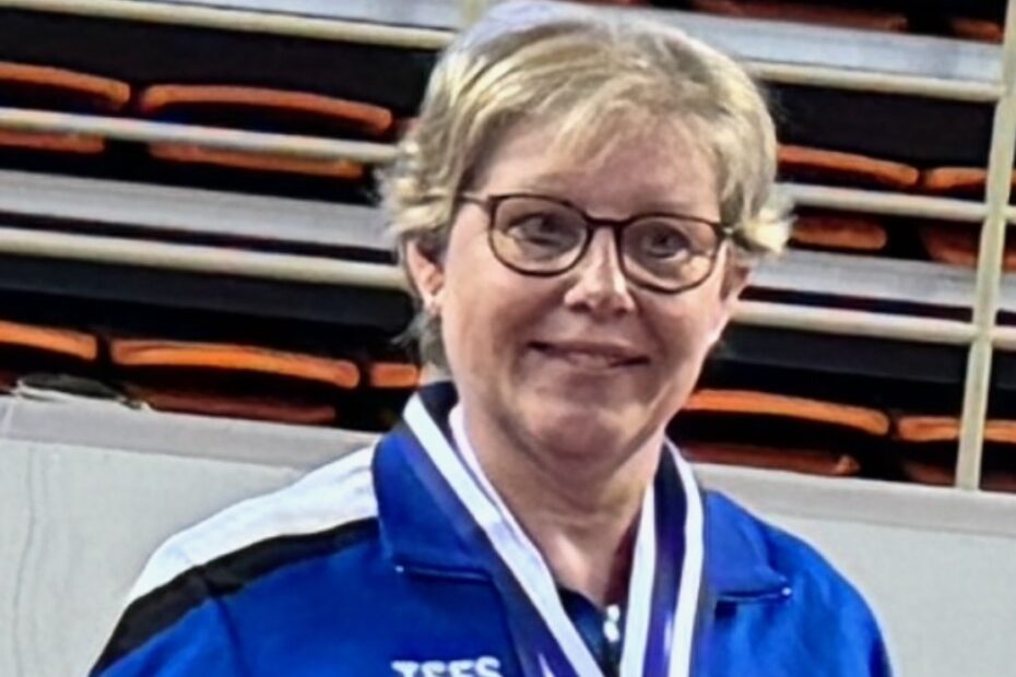 Picture of Joy Paul with her medals dressed in her Scotland table tennis jacket