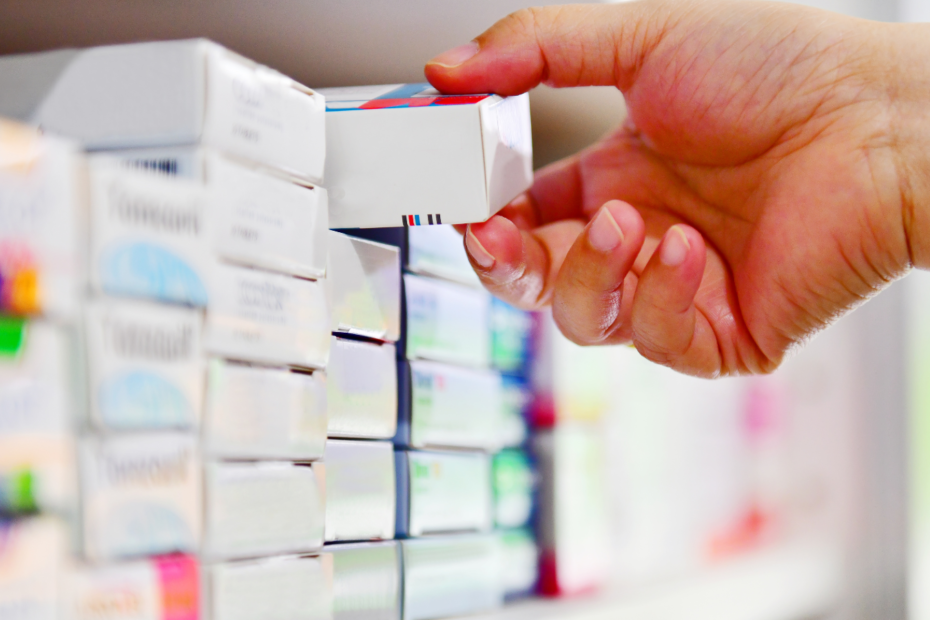 Hand reaching onto shelf with boxes of medicine.