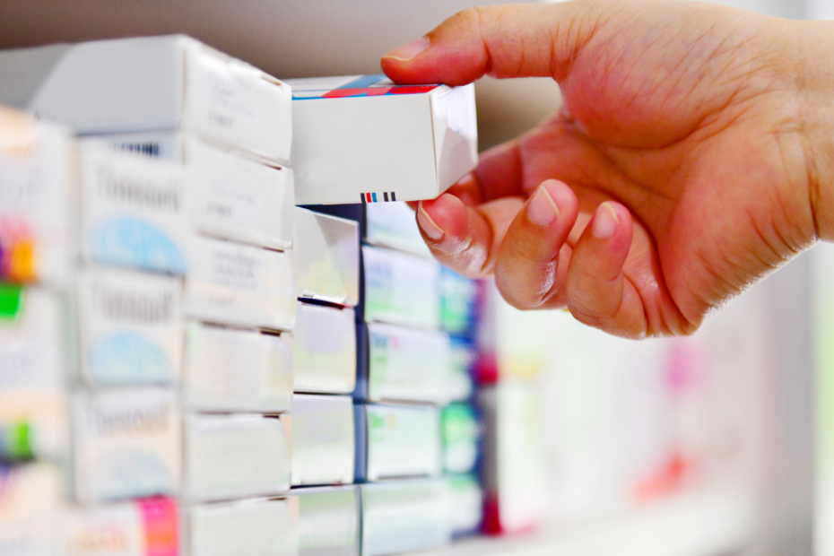 Hand reaching out onto shelf grabbing boxes medicine.