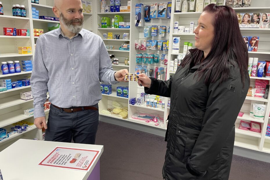 Woman handing over unused antibiotics to community pharmacy
