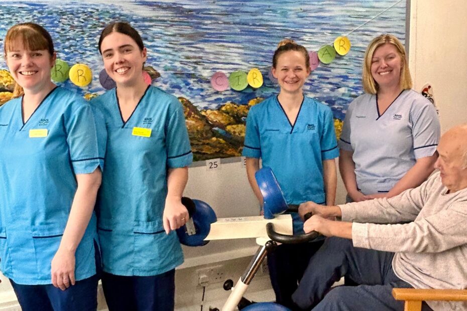 University Hospital Crosshouse Physiotherapy team pictured in front of the Arran route with patient David, 86 years as cycles