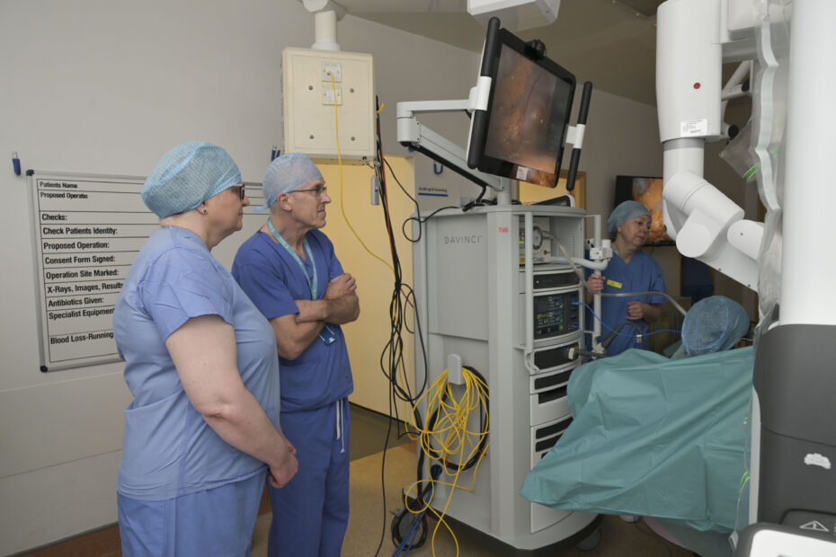 Two people in a medical theatre observing a robotic assisted surgery procedure.
