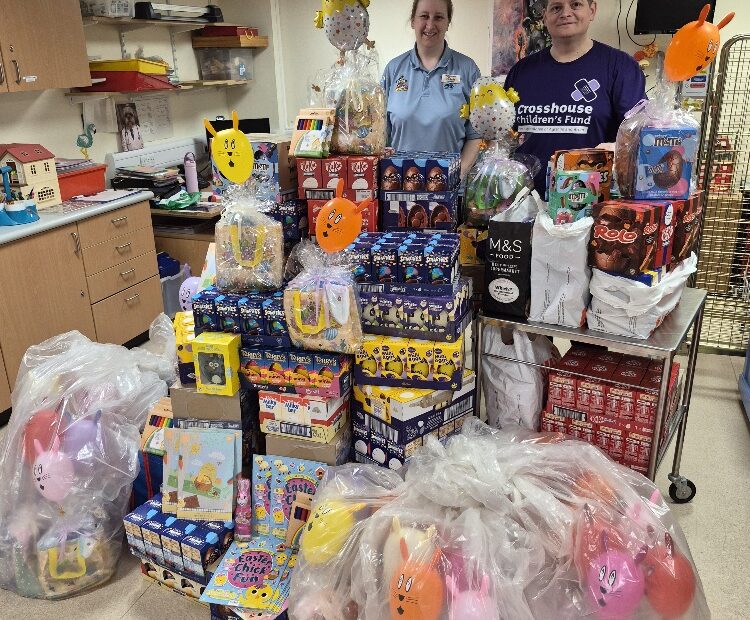 NHS Ayrshire & Arran Hospital Play Worker Michelle Dodds and Michael Kirkum Jr. standing in front of easter eggs and gifts pilled high in front of them