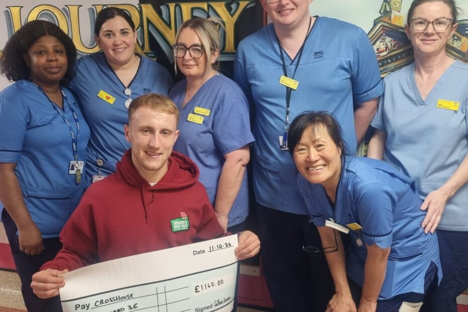 A group of nursing staff being presented with a large cheque by a man